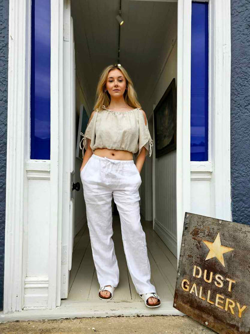 Main shot: "Mt Buster linen pants in natural white, relaxed wide leg with drawstring waist, worn outside Dust Gallery Ranfurly, handmade by Lohi Linen in Central Otago, New Zealand"