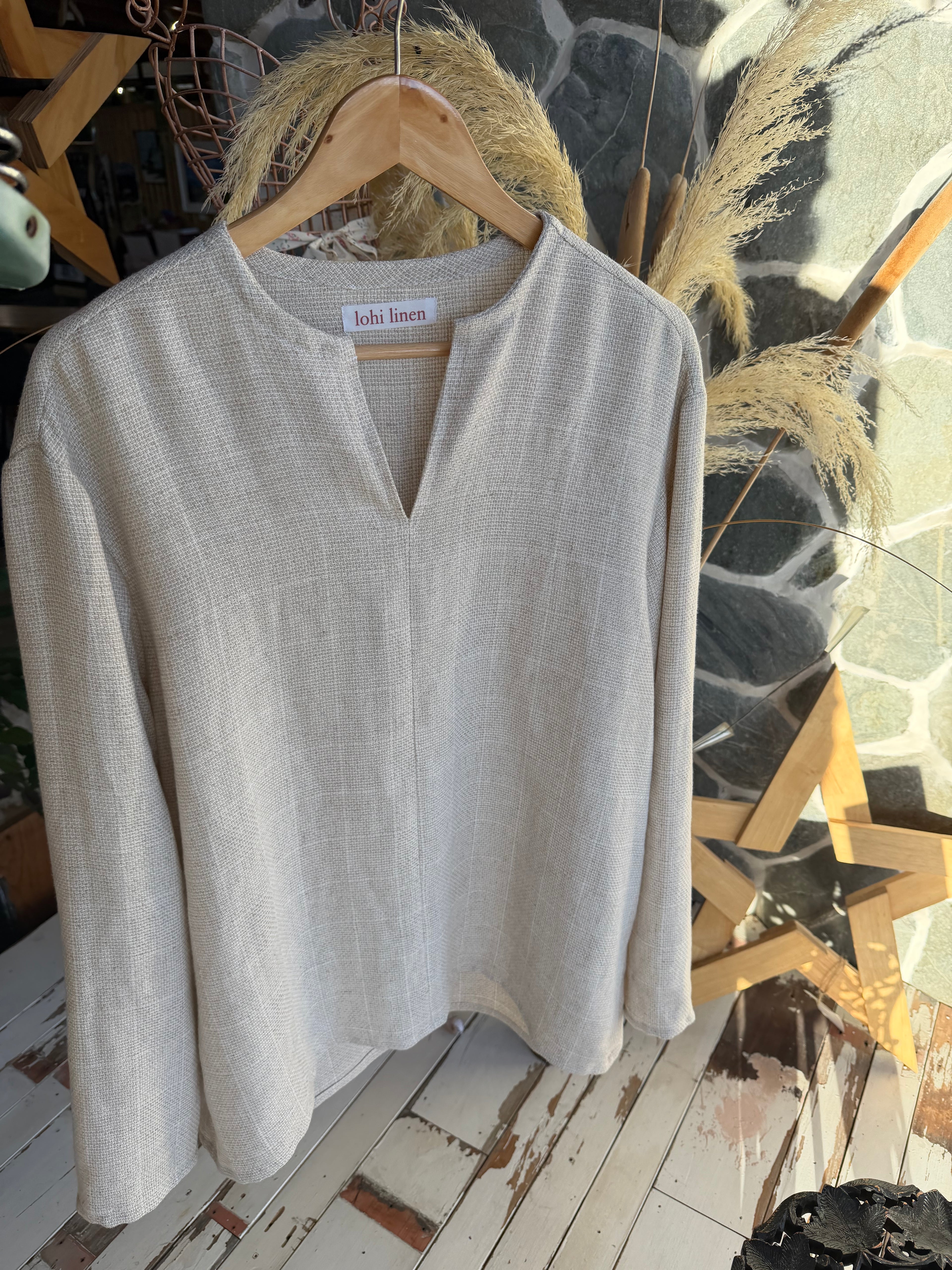 "Natural oatmeal linen top on a hanger, relaxed V-neck with long sleeves, handmade by Lohi Linen in Central Otago, New Zealand"