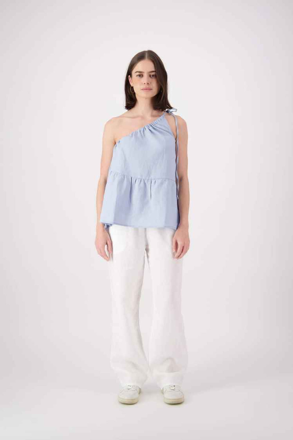 Front view white pants: "Ranfurly linen top in sky blue styled with white linen pants, relaxed one-shoulder silhouette, handmade by Lohi Linen in Central Otago"