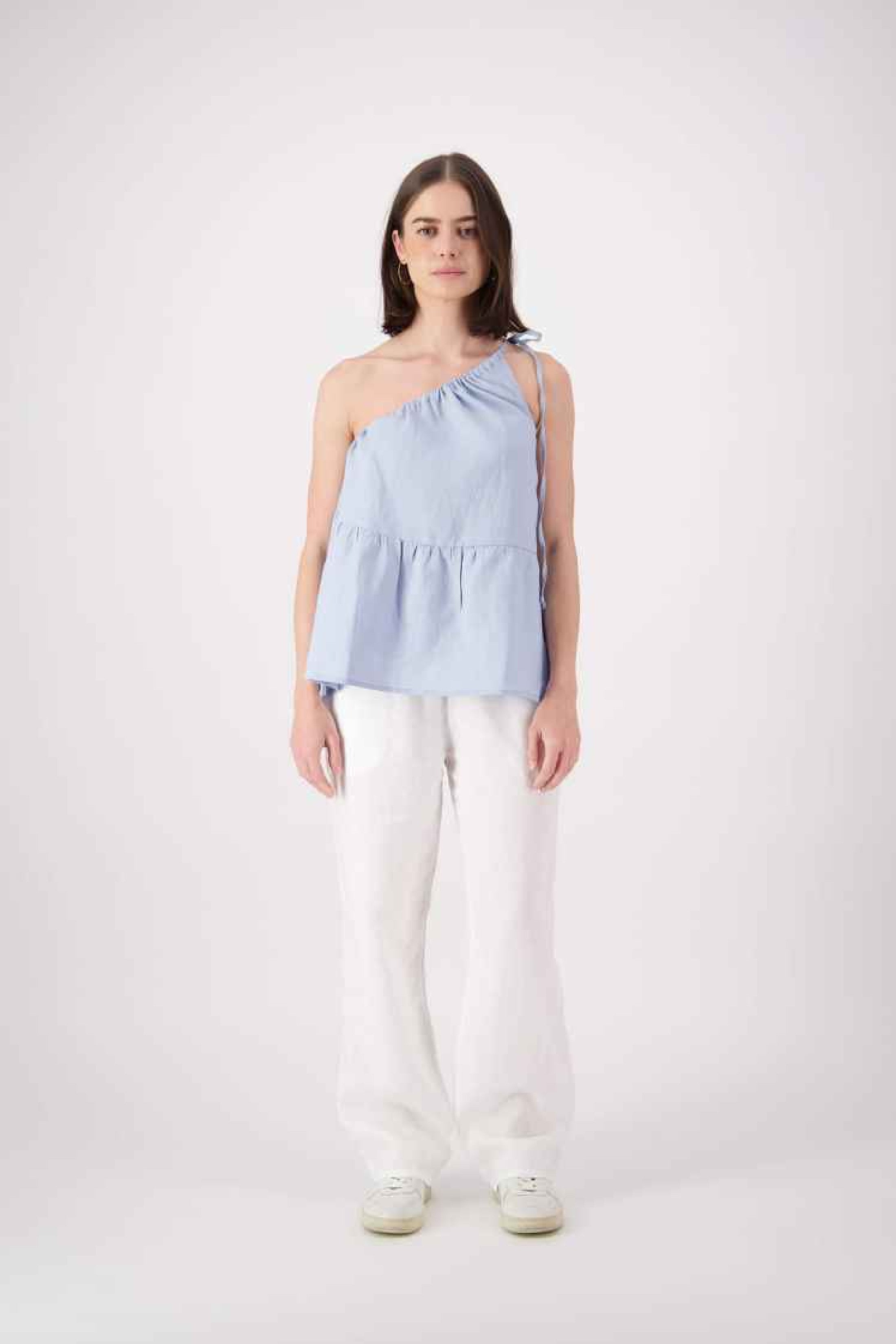 Front view white pants: "Ranfurly linen top in sky blue styled with white linen pants, relaxed one-shoulder silhouette, handmade by Lohi Linen in Central Otago"