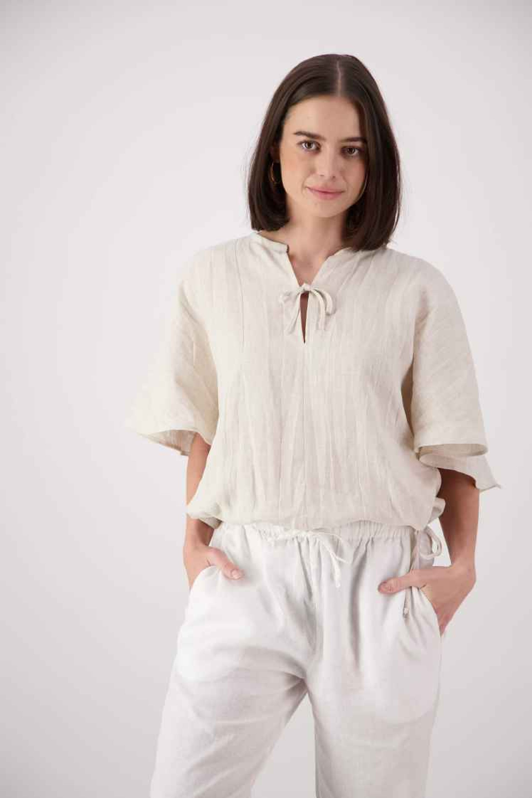 Front view white: "Paerau linen top in natural oat front view showing V-neck tie detail and pintuck panel, handmade by Lohi Linen"