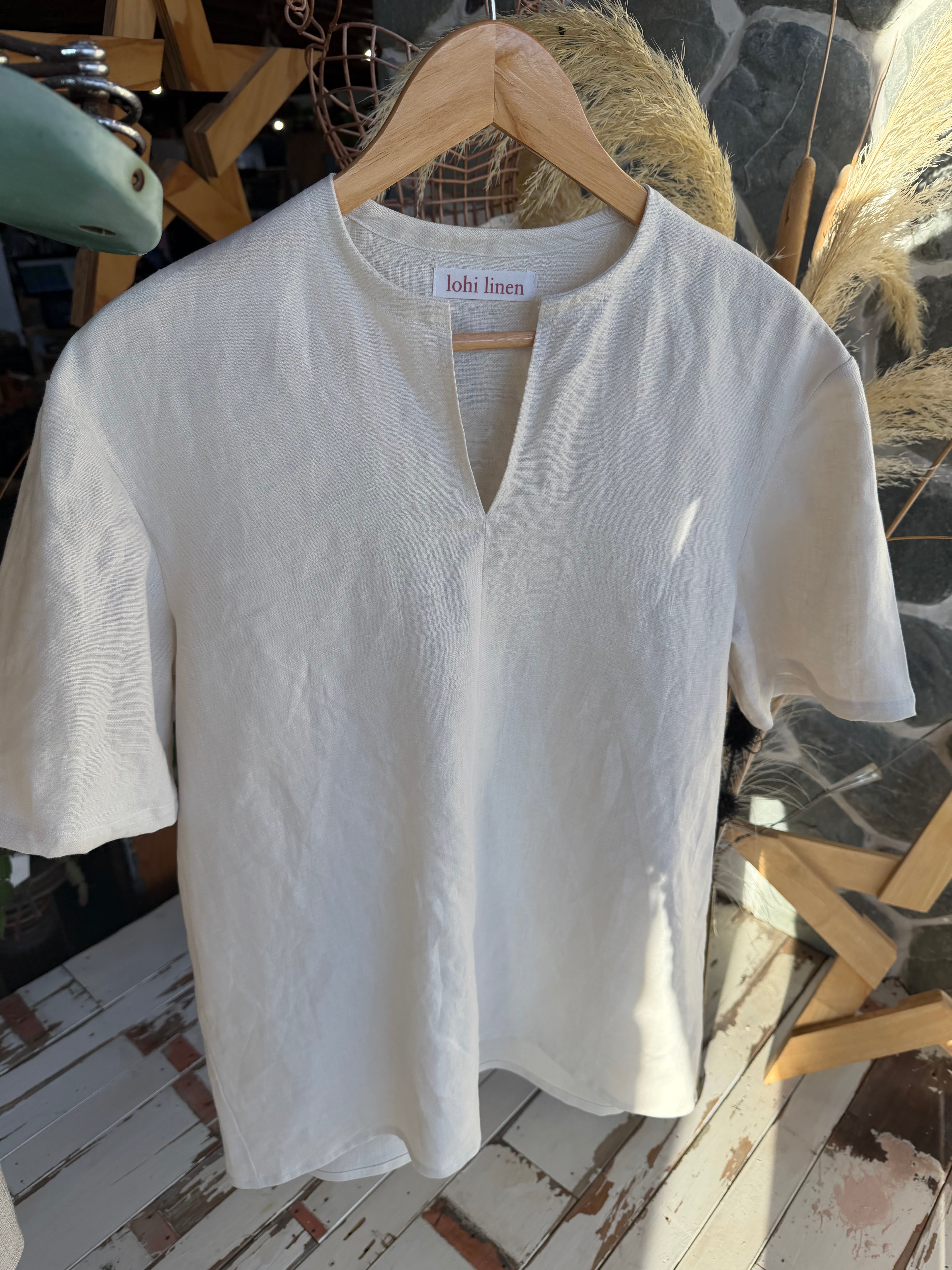 Shirt on hanger: "St Bathans linen t-shirt in Silvered Almond on hanger showing notch neckline detail, handmade by Lohi Linen in Central Otago, New Zealand