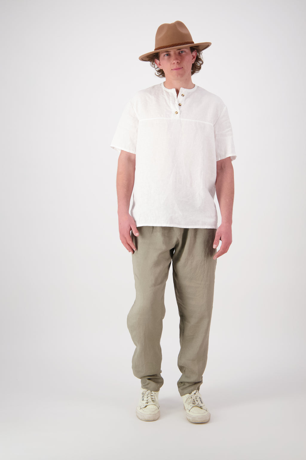 Front view white (stone): "Hawkdun linen top in stone worn with olive linen pants, relaxed henley short sleeve, handmade by Lohi Linen in Central Otago"