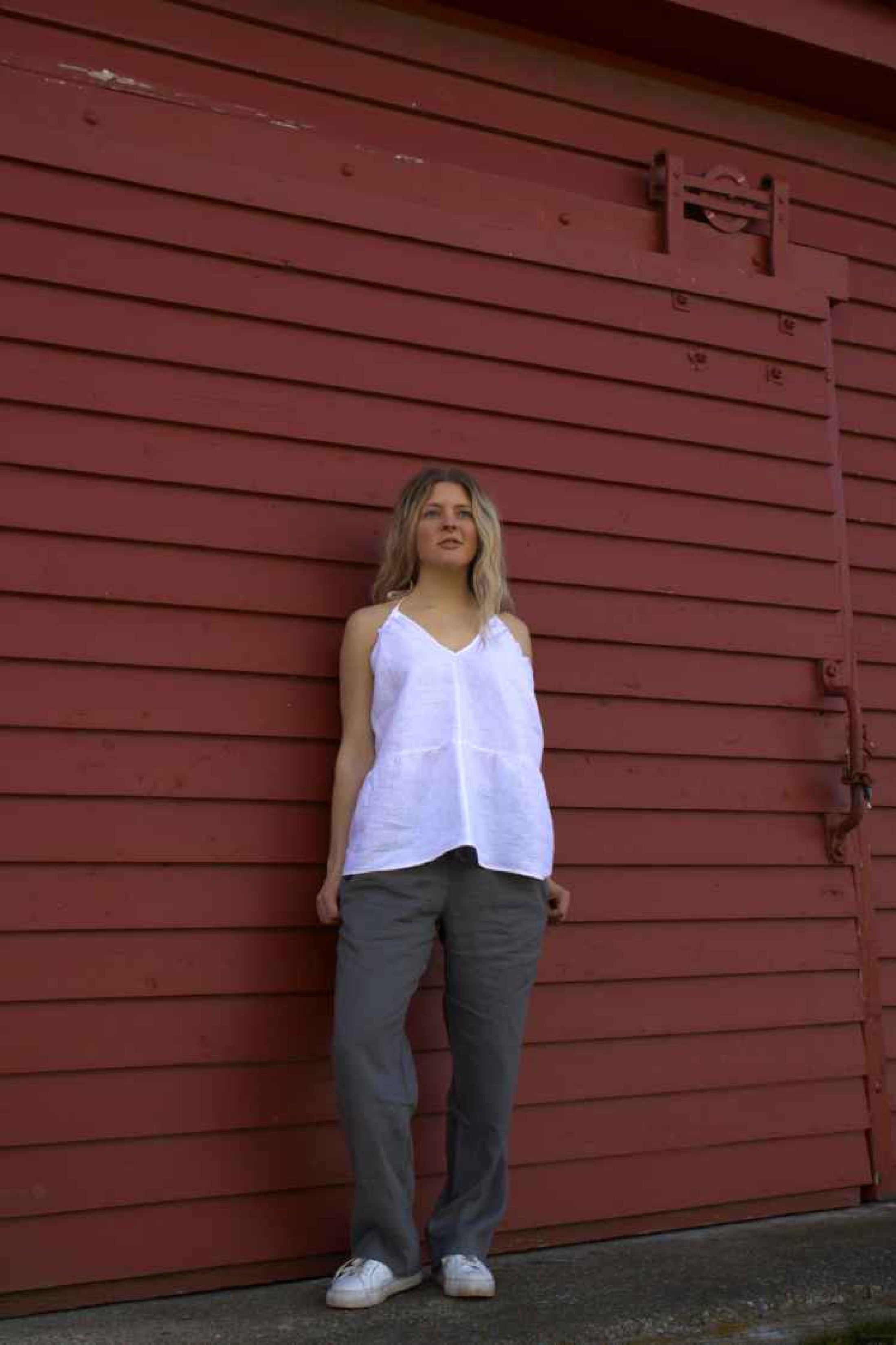 Red wall shot: "Mt Buster linen pants in charcoal grey, relaxed wide leg worn against red wall, handmade by Lohi Linen in Ranfurly, New Zealand"
